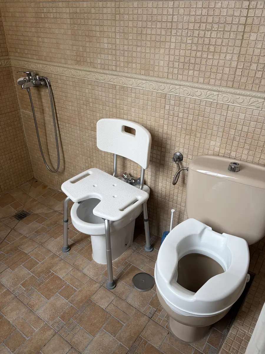 Silla de ducha y alza de inodoro en un baño adaptado