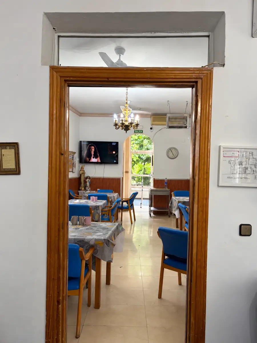 Vista del comedor a través de la puerta, con mesas y salida al jardín