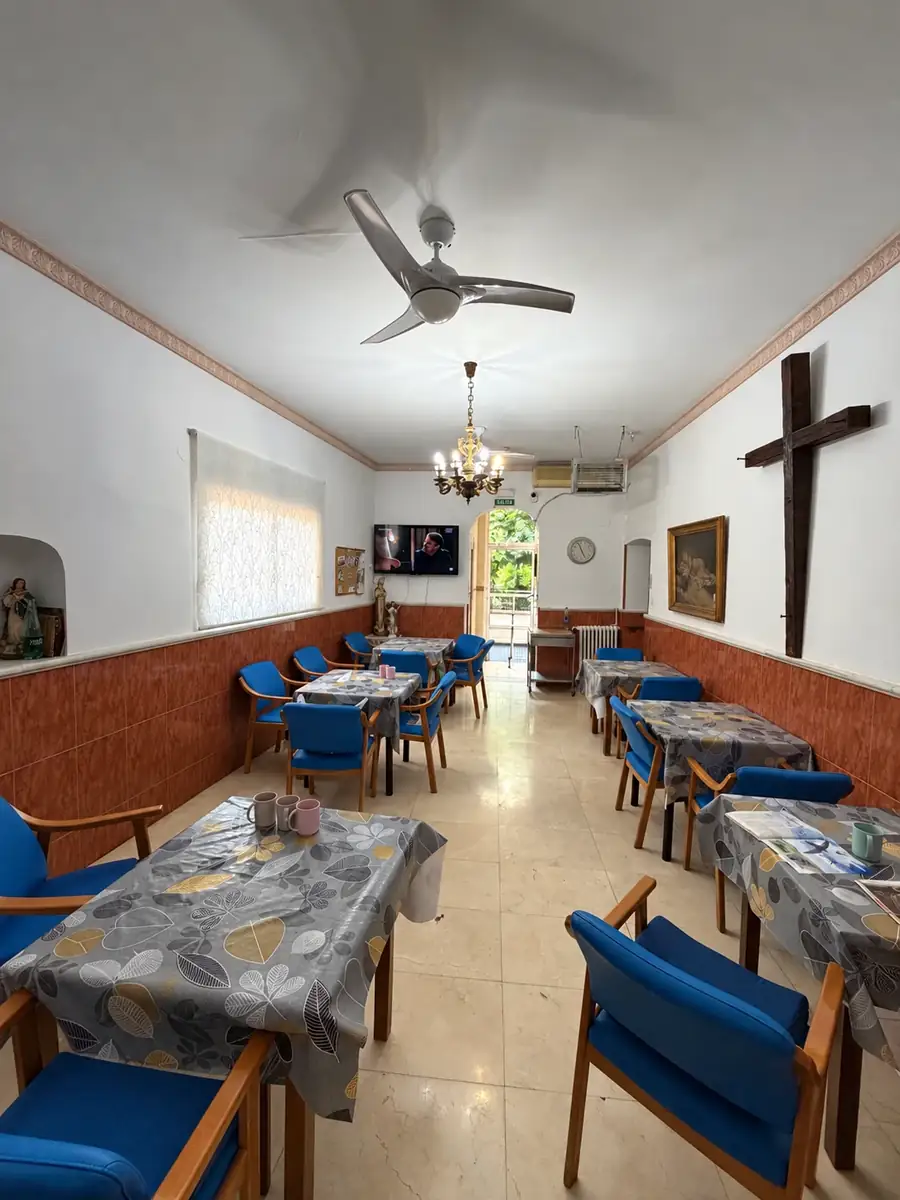Comedor alargado con mesas, sillas azules, lámpara y salida al jardín