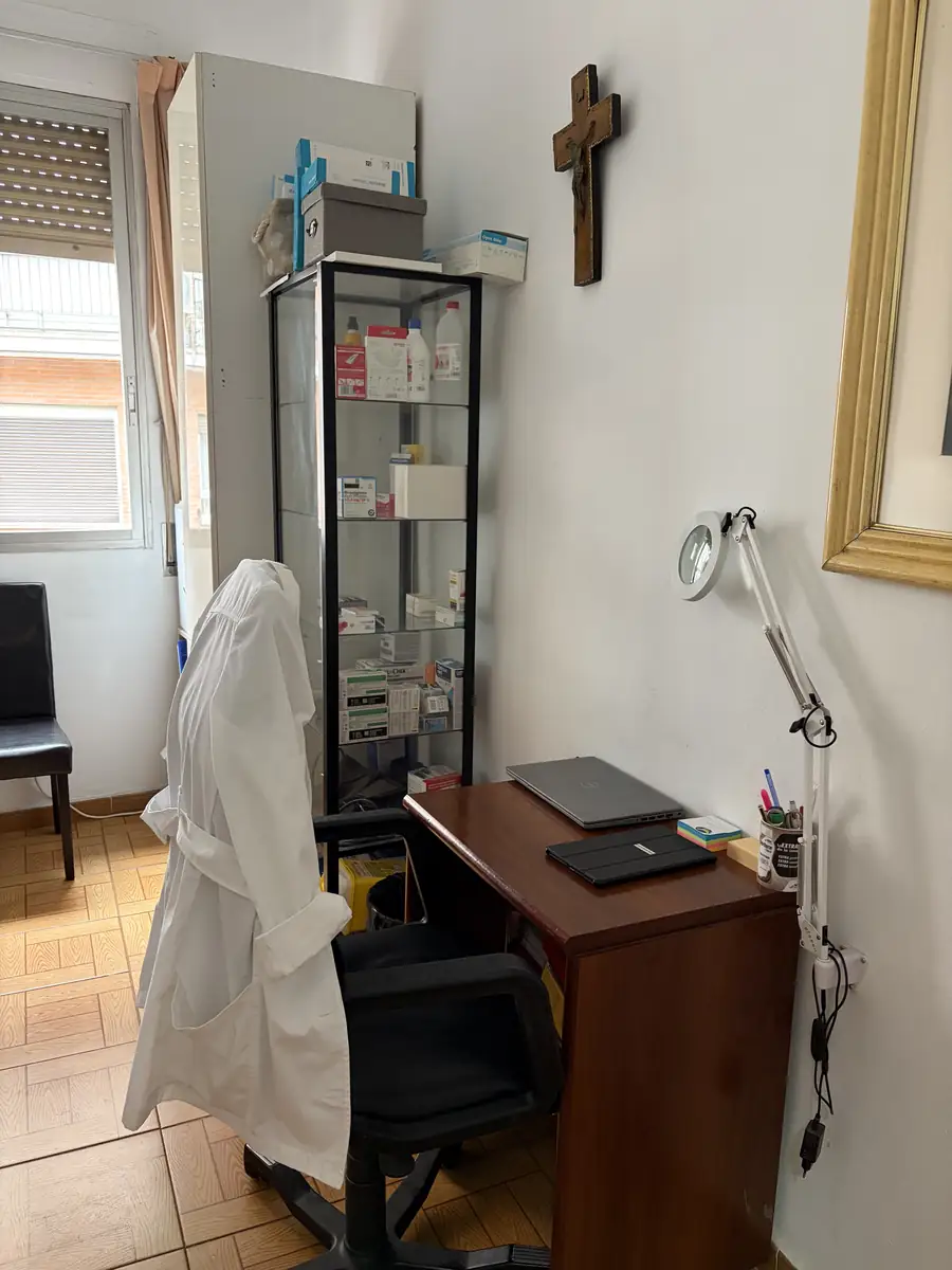 Consulta de la enfermería, con escritorio, bata y vitrina de material sanitario