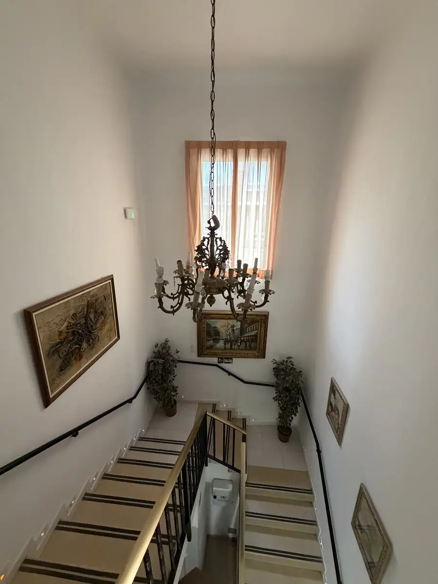 Hueco de la escalera con lámpara de araña y cuadros