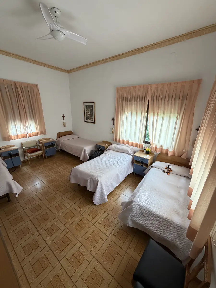 Habitación amplia con camas, dos ventanas y ventilador de techo