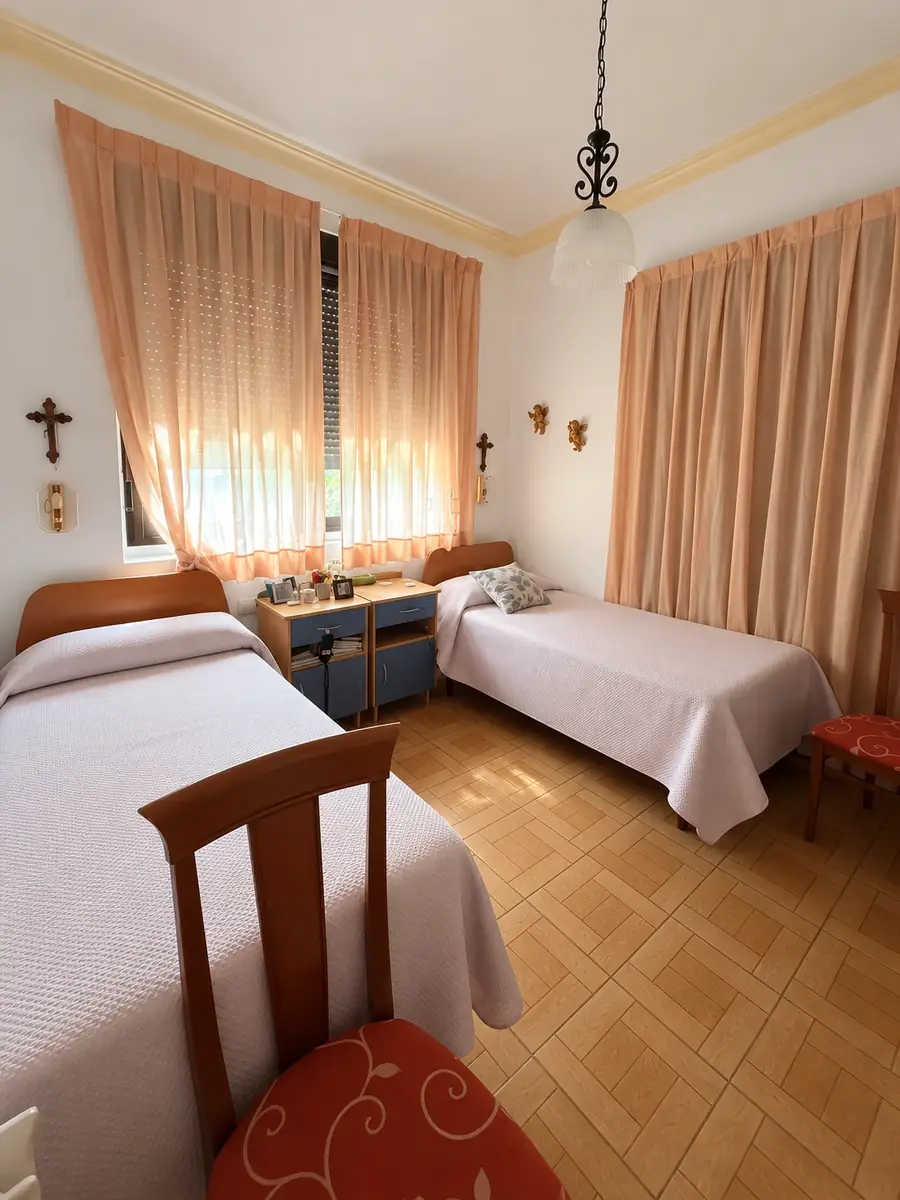 Habitación doble con dos camas, lámpara colgante, angelitos y cortinas