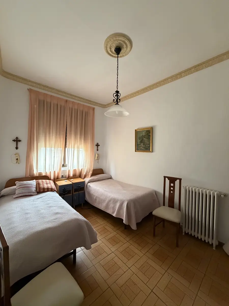 Habitación doble con dos camas, cuadro y ventana con cortinas