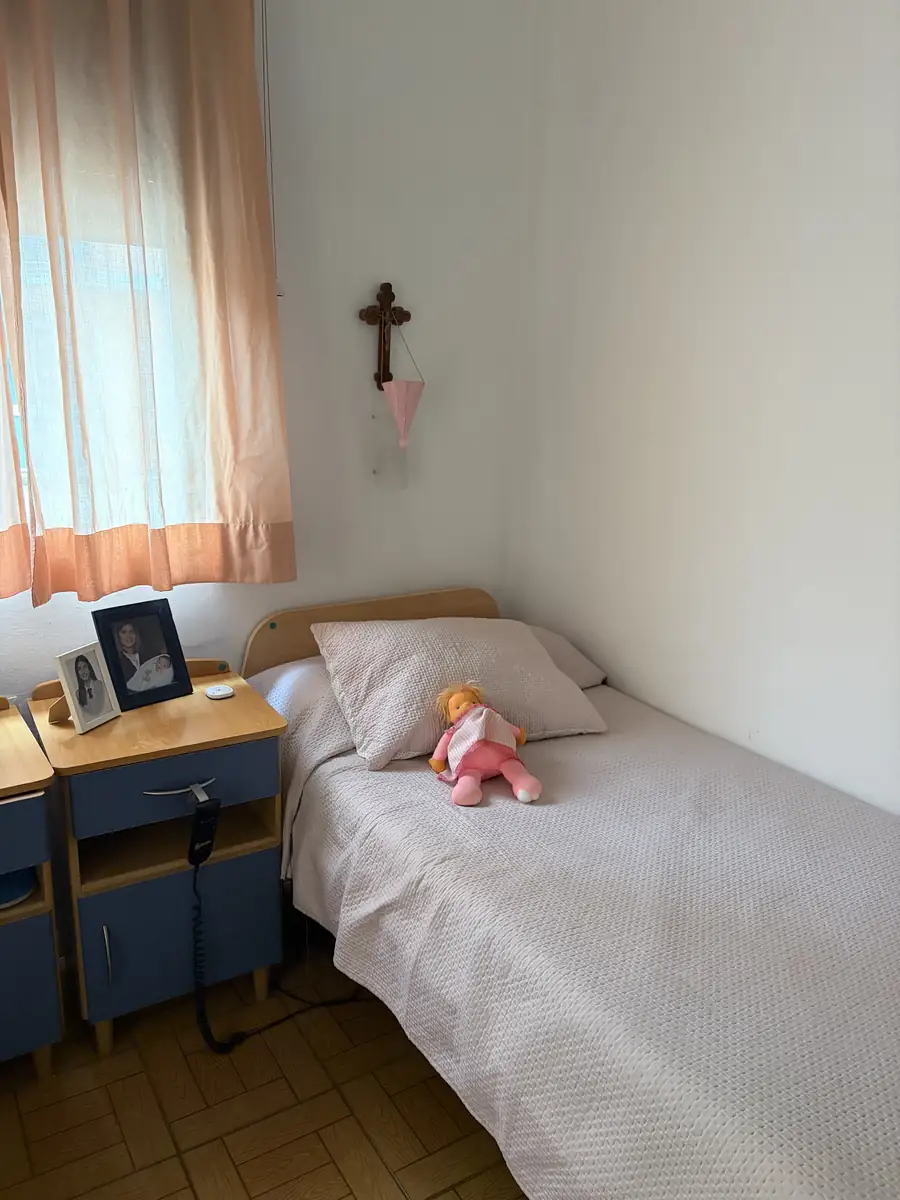 Cama con fotos familiares en la mesilla y un muñeco de recuerdo