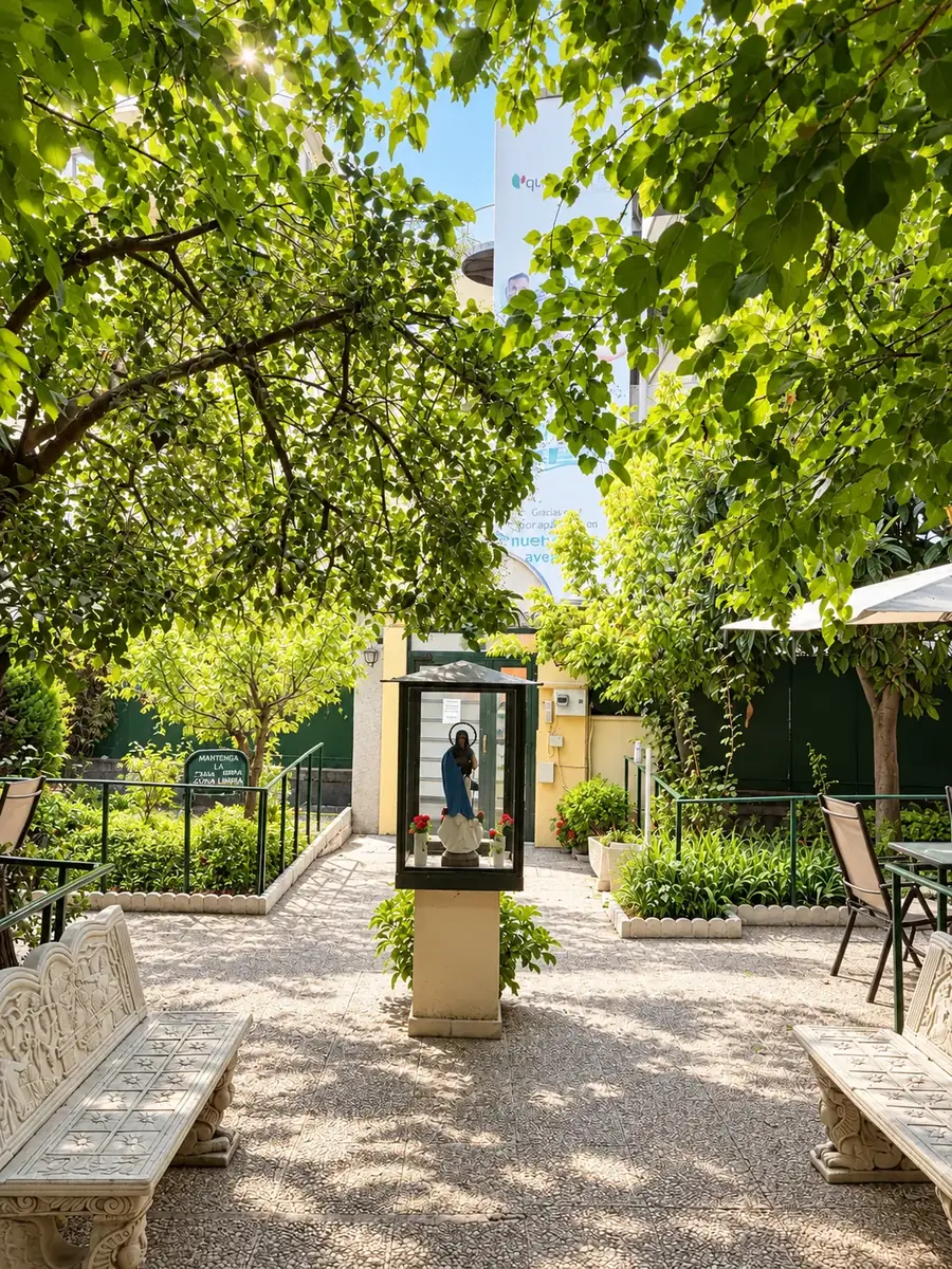 Camino del jardín con bancos de piedra y la hornacina de la Virgen al fondo