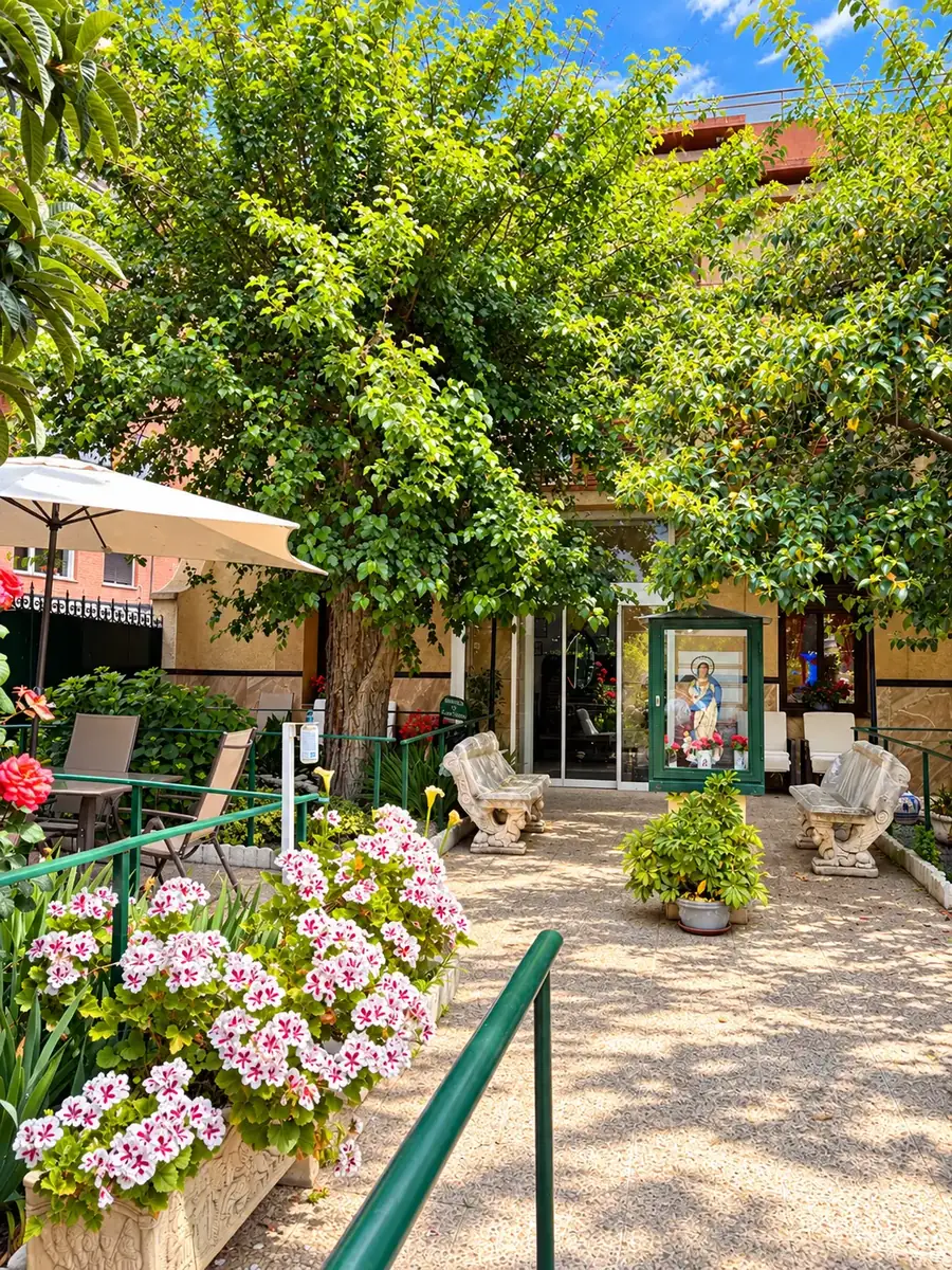 Jardín de la entrada con flores, sombrilla y bancos de piedra