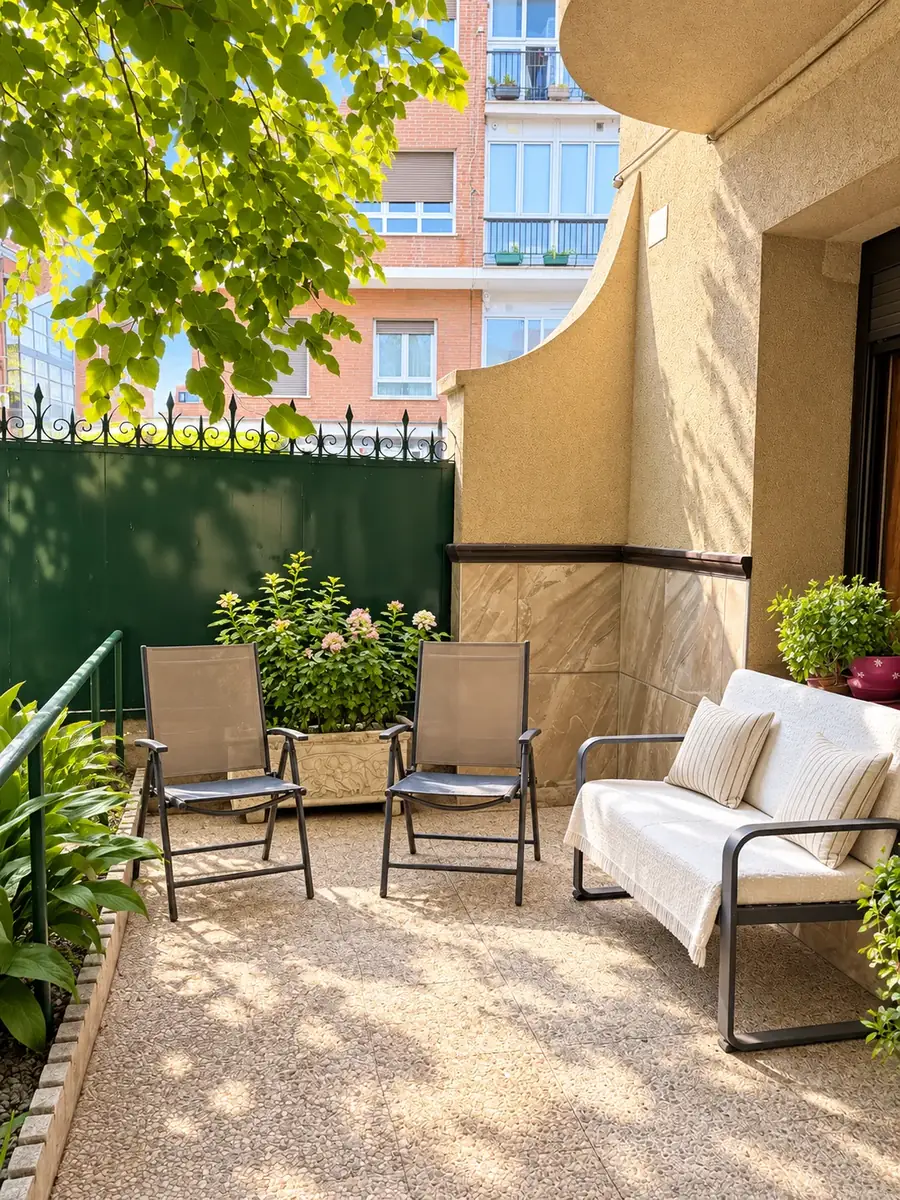 Rincón soleado del jardín con dos sillas, sofá exterior y flores