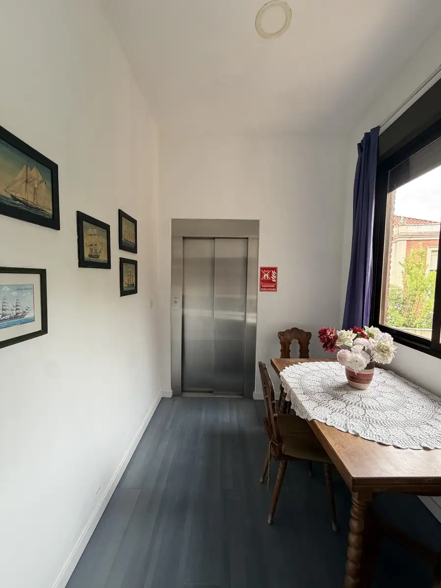 Pasillo con mesa, flores y el ascensor al fondo