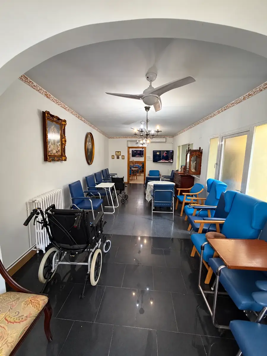 Sala de estar alargada con butacas azules, cuadros y lámparas