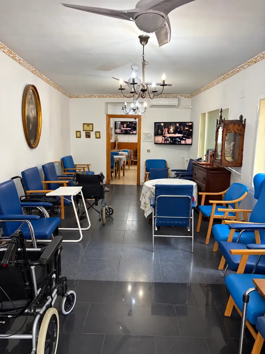 Sala de estar con butacas azules, mesa camilla y lámparas