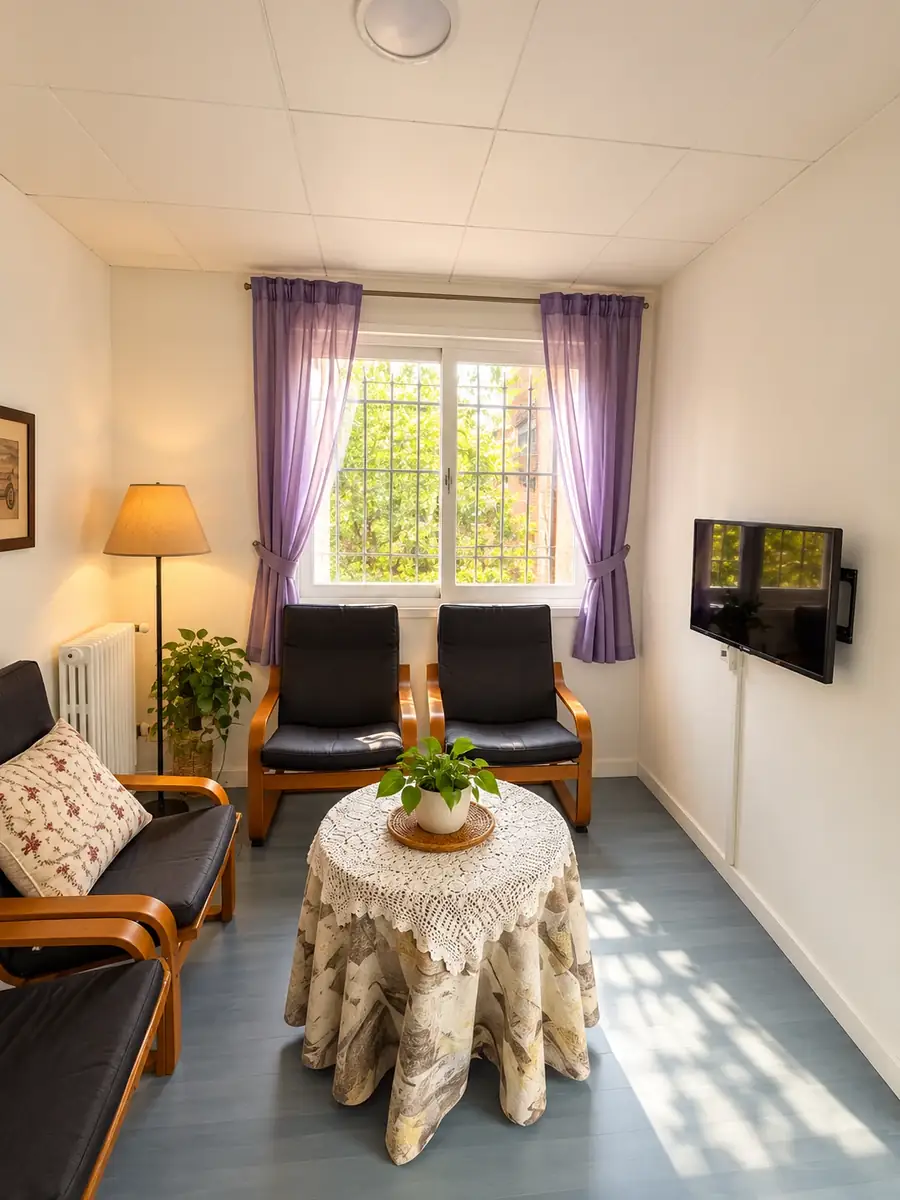 Salita de estar con butacas, mesa camilla, lámpara de pie y ventana luminosa