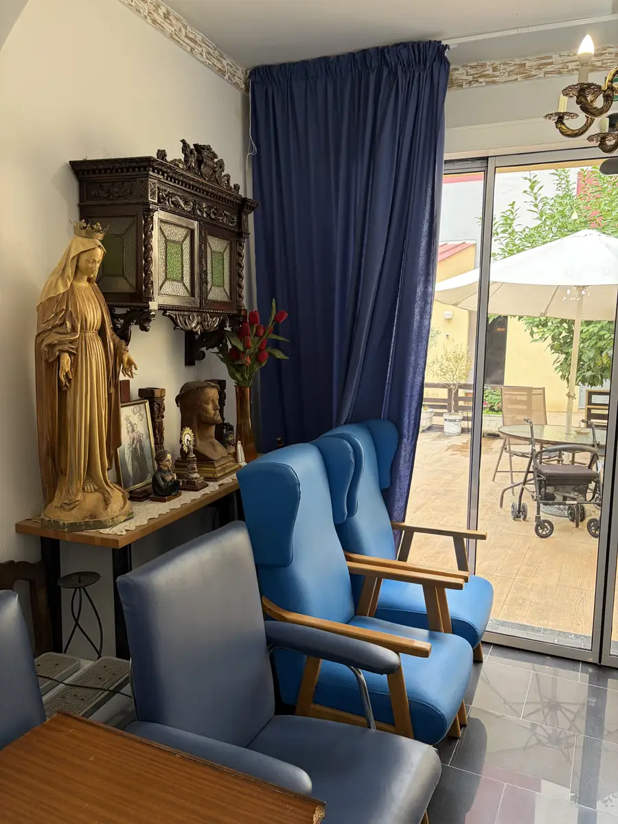 Butacas azules junto a una imagen de la Virgen y la puerta a la terraza