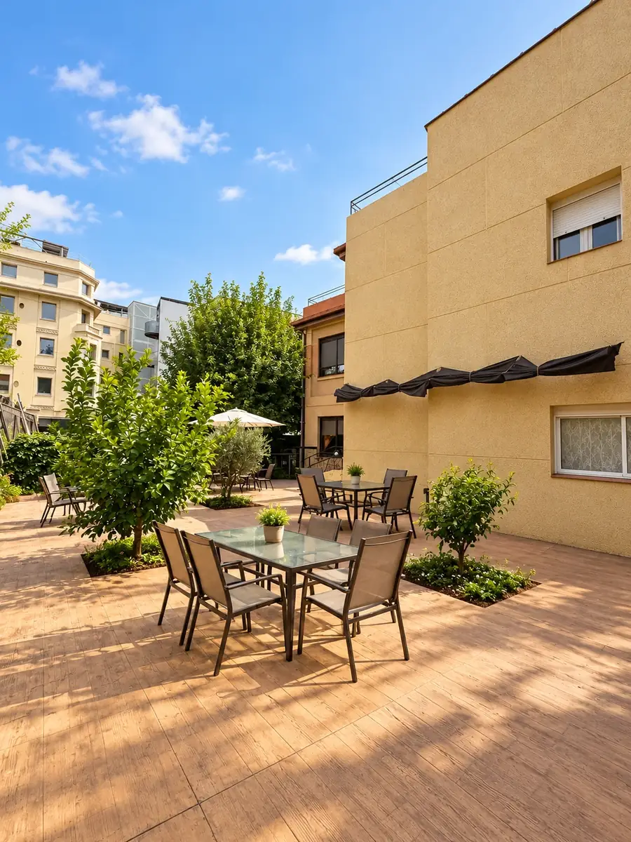 Terraza amplia con mesas, árboles y el edificio al fondo