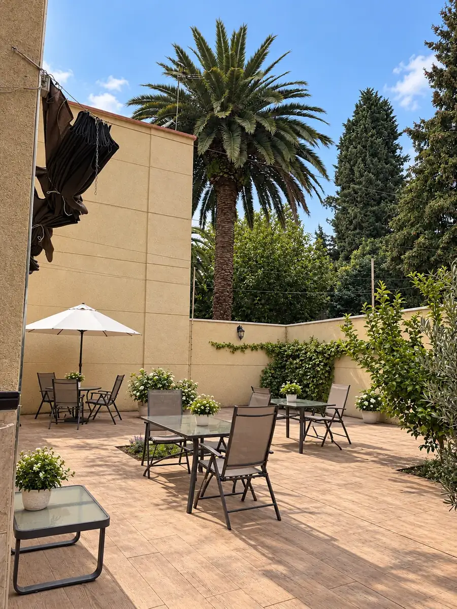 Terraza soleada con mesas, sombrilla y una gran palmera